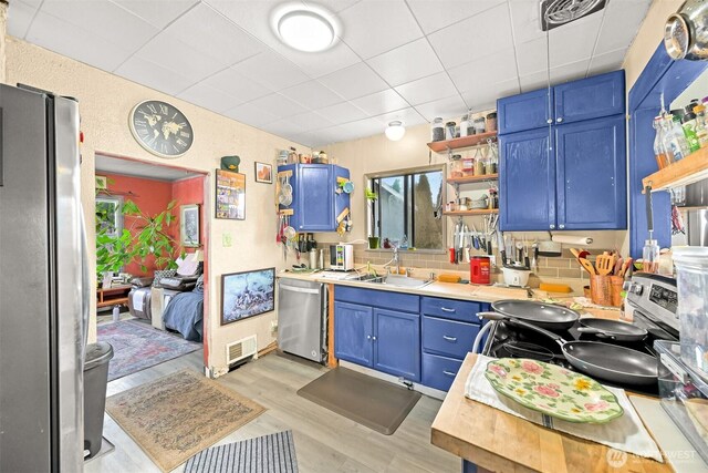 1501 Lakeway Dr, Bellingham, WA 98225 - kitchen featuring appliances with stainless steel finishes, blue cabinetry, open shelves, light countertops, and a paneled ceiling