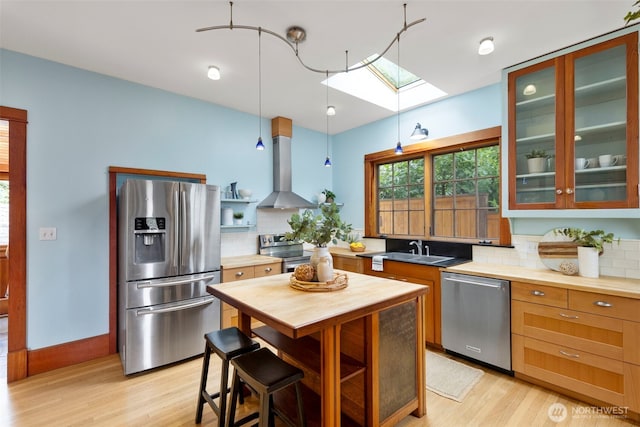 832 Willow St, Port Townsend, WA 98368 - kitchen with appliances with stainless steel finishes, range hood, a skylight, decorative backsplash, and light wood finished floors