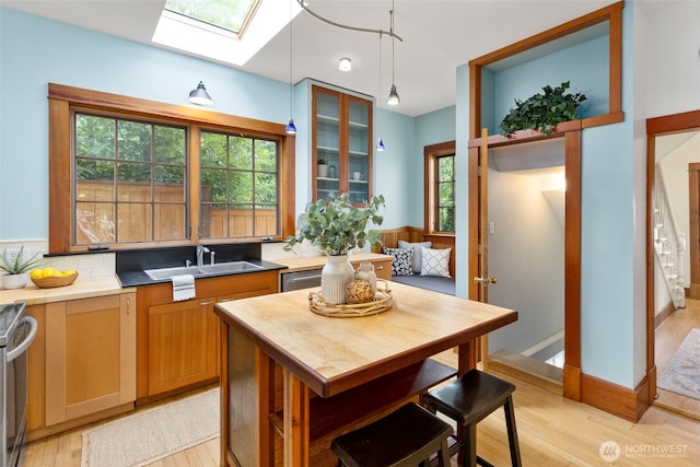 832 Willow St, Port Townsend, WA 98368 - kitchen featuring a skylight, light wood-type flooring, pendant lighting, stainless steel appliances, and glass insert cabinets