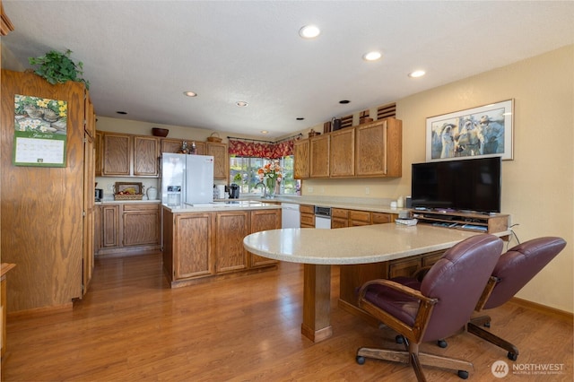 1807 Bradley Dr, Anacortes, WA 98221 - kitchen with white appliances, light countertops, brown cabinets, a breakfast bar, and light wood-style flooring