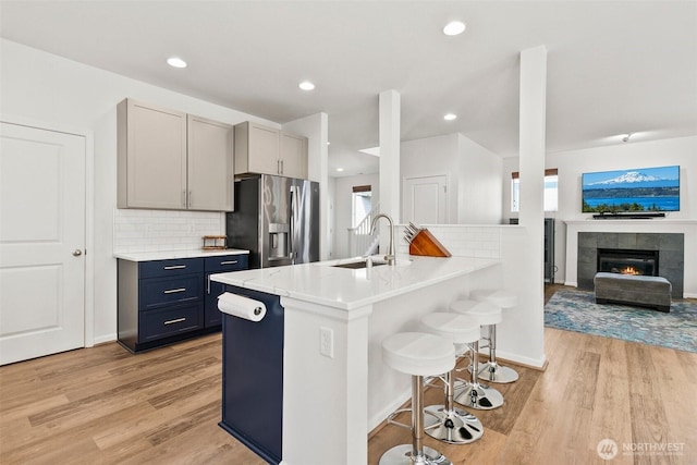 21552 SE 275th Ct, Maple Valley, WA 98038 - kitchen with stainless steel fridge with ice dispenser, a breakfast bar area, light wood-style floors, tasteful backsplash, and recessed lighting