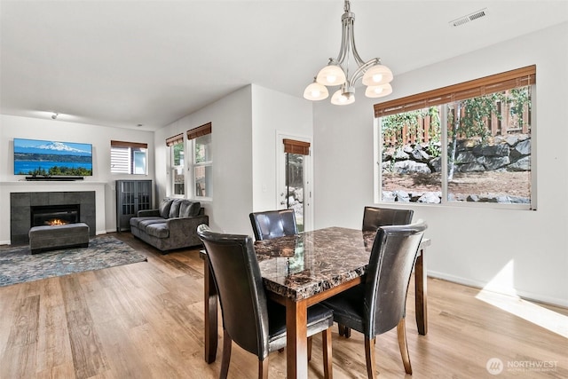 21552 SE 275th Ct, Maple Valley, WA 98038 - dining space with light wood finished floors, a fireplace, and a chandelier