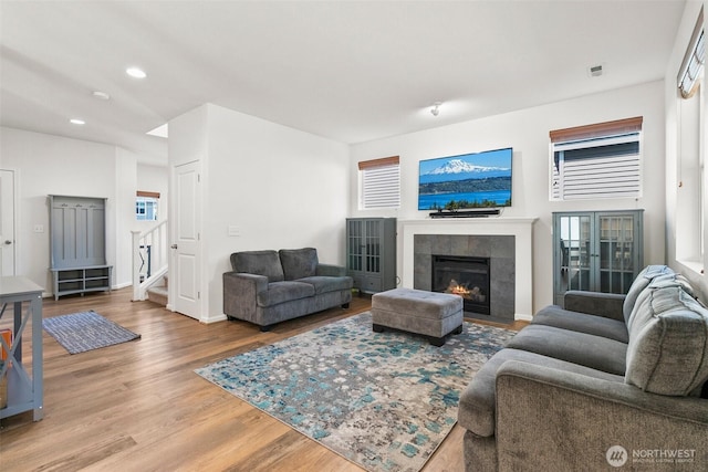 21552 SE 275th Ct, Maple Valley, WA 98038 - living area with wood finished floors, stairs, a tiled fireplace, recessed lighting, and plenty of natural light