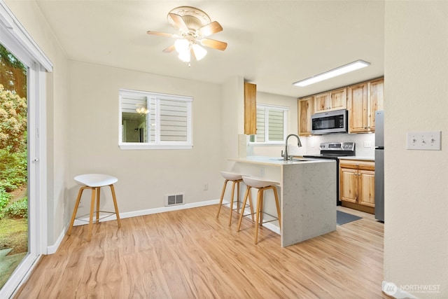 4617 Grandview Dr W Unit D, Tacoma, WA 98466 - kitchen with appliances with stainless steel finishes, light wood finished floors, a breakfast bar area, a peninsula, and ceiling fan