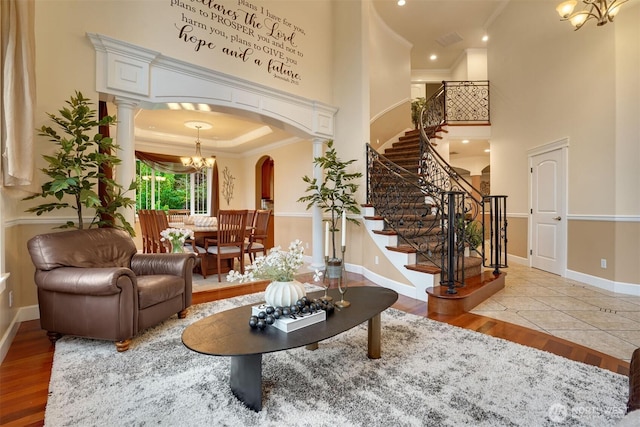 24702 64th Ave E, Graham, WA 98338 - living room featuring a chandelier, crown molding, arched walkways, wood finished floors, and a towering ceiling