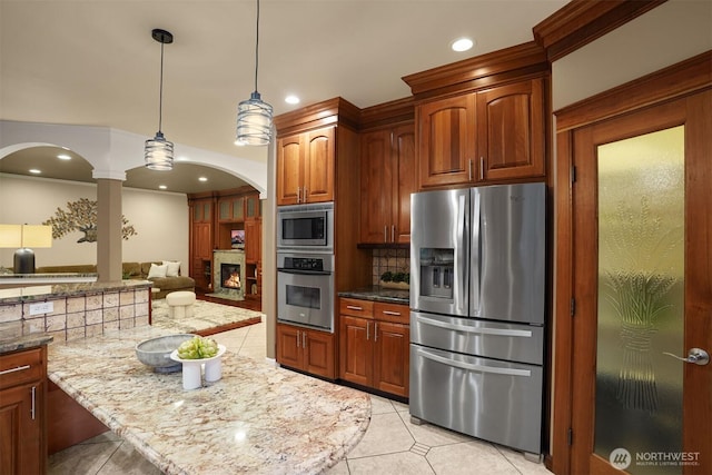 24702 64th Ave E, Graham, WA 98338 - kitchen featuring appliances with stainless steel finishes, arched walkways, tasteful backsplash, light tile patterned flooring, and light stone counters