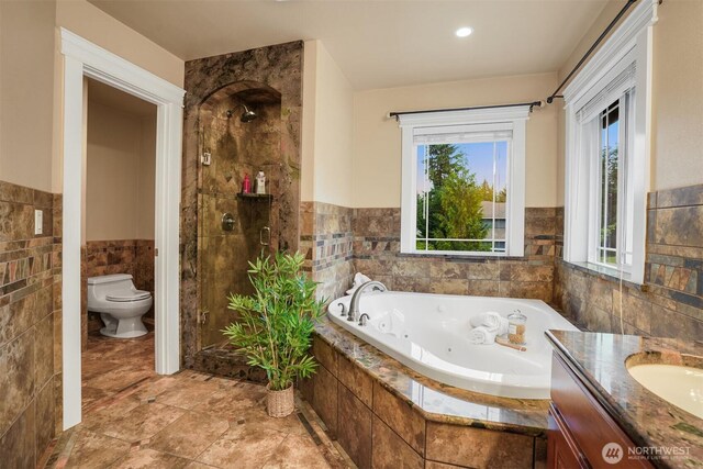 24702 64th Ave E, Graham, WA 98338 - full bathroom with tile walls, a whirlpool tub, a shower stall, wainscoting, and vanity