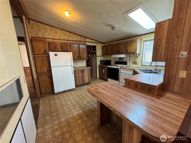 31600 126th Ave SE Unit 100, Auburn, WA 98092 - kitchen featuring white appliances, vaulted ceiling, under cabinet range hood, a peninsula, and brown cabinets