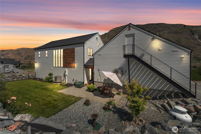 485 Hidden Ln, Chelan, WA 98816 - back of house at dusk with a patio, a lawn, and a mountain view
