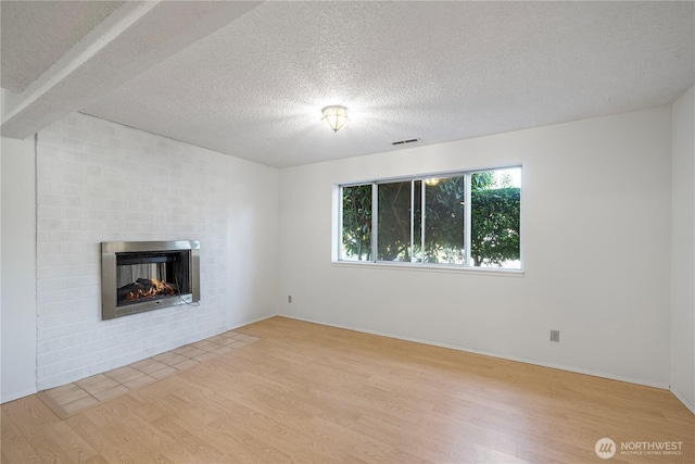 33513 35th Ave SW, Federal Way, WA 98023 - unfurnished living room featuring light wood-type flooring, a fireplace, and a textured ceiling