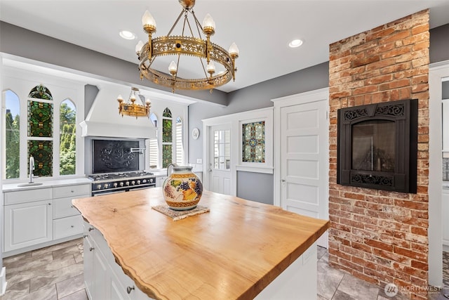 4410 N 45th St, Tacoma, WA 98407 - kitchen with a chandelier, high end stove, butcher block countertops, a fireplace, and white cabinetry