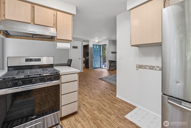 1717 14th Ave SE, Olympia, WA 98501 - kitchen with stainless steel appliances, under cabinet range hood, washer / clothes dryer, light countertops, and light wood-style flooring