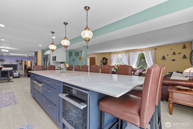 6830 SE Arlington Pl, Port Orchard, WA 98367 - kitchen with open floor plan, blue cabinets, light countertops, a breakfast bar, and recessed lighting