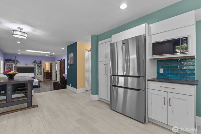 6830 SE Arlington Pl, Port Orchard, WA 98367 - kitchen featuring freestanding refrigerator, built in microwave, dark countertops, tasteful backsplash, and open floor plan