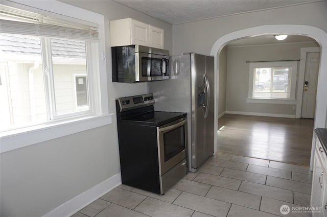 608 S 6th Ave, Kelso, WA 98626 - kitchen with appliances with stainless steel finishes, arched walkways, white cabinetry, and light tile patterned floors