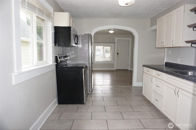 608 S 6th Ave, Kelso, WA 98626 - kitchen with stainless steel appliances, open shelves, arched walkways, dark countertops, and white cabinets