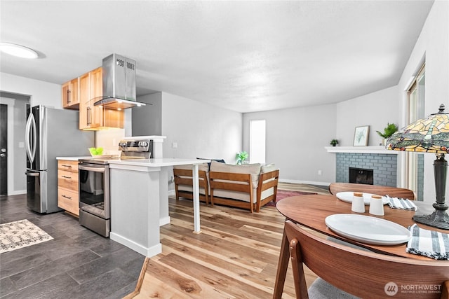 3104 Bill Mcdonald Pkwy Unit D104, Bellingham, WA 98225 - kitchen with appliances with stainless steel finishes, island exhaust hood, light brown cabinetry, light countertops, and a brick fireplace