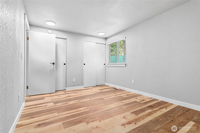 3104 Bill Mcdonald Pkwy Unit D104, Bellingham, WA 98225 - unfurnished bedroom featuring multiple closets, wood finished floors, and a textured wall
