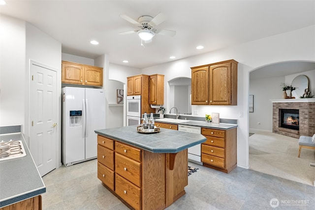 7506 Hawkstone Ave SW, Port Orchard, WA 98367 - kitchen with white appliances, arched walkways, a ceiling fan, a center island, and a fireplace