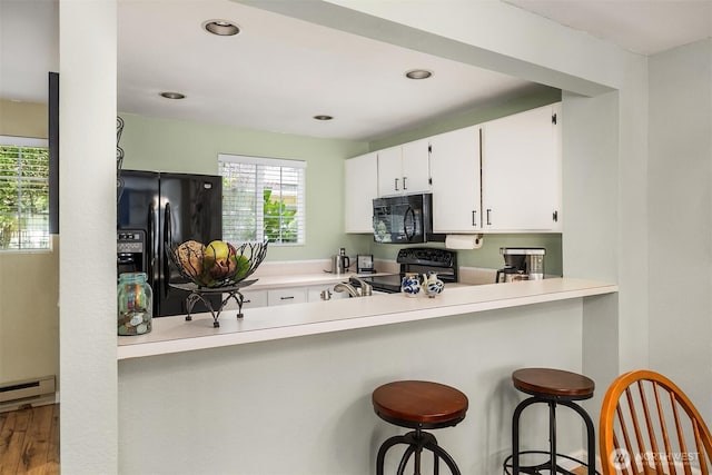 15600 116th Ave NE Unit E4, Bothell, WA 98011 - kitchen featuring black appliances, white cabinets, baseboard heating, a breakfast bar, and light countertops
