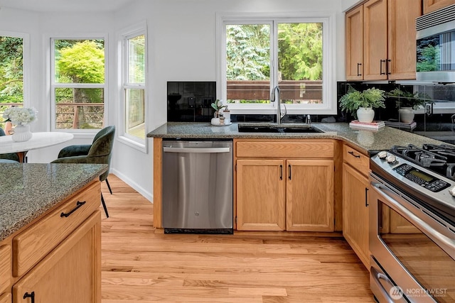 1125 Hemlock Ave SW, North Bend, WA 98045 - kitchen with appliances with stainless steel finishes, light wood-type flooring, plenty of natural light, and dark stone counters