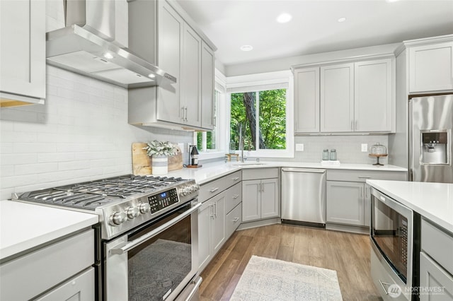 7223 NE 118th Ct, Kirkland, WA 98034 - kitchen featuring appliances with stainless steel finishes, wall chimney exhaust hood, gray cabinetry, tasteful backsplash, and light countertops