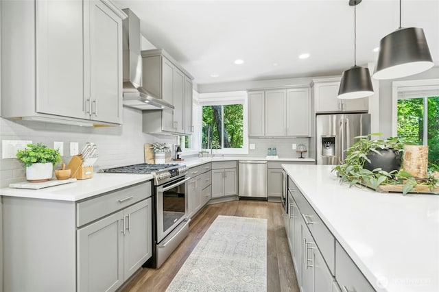 7223 NE 118th Ct, Kirkland, WA 98034 - kitchen featuring appliances with stainless steel finishes, wall chimney exhaust hood, healthy amount of natural light, light wood finished floors, and recessed lighting