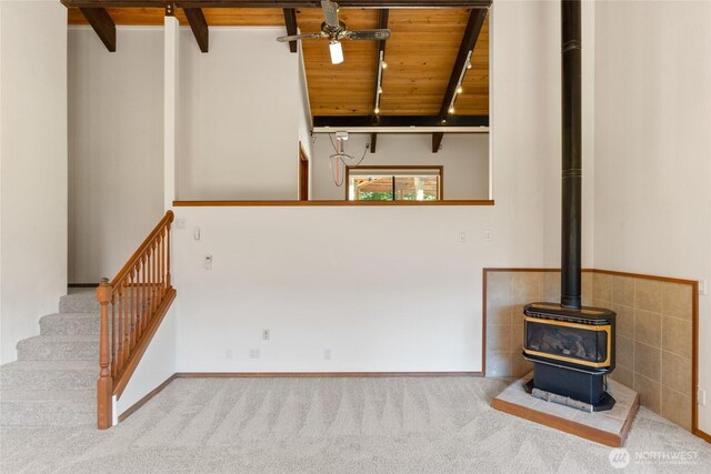 16537 Lakeview Dr, Leavenworth, WA 98826 - unfurnished living room featuring a wooden ceiling with exposed beams, a ceiling fan, a wood stove, carpet floors, and stairs