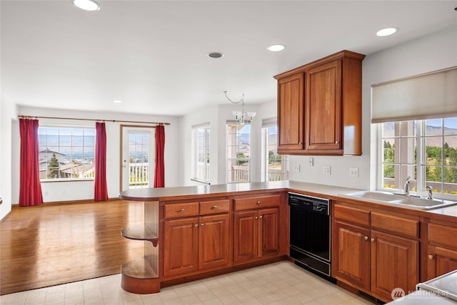 3505 Kimberly Ct, Wenatchee, WA 98801 - kitchen with black dishwasher, a peninsula, brown cabinets, a chandelier, and healthy amount of natural light