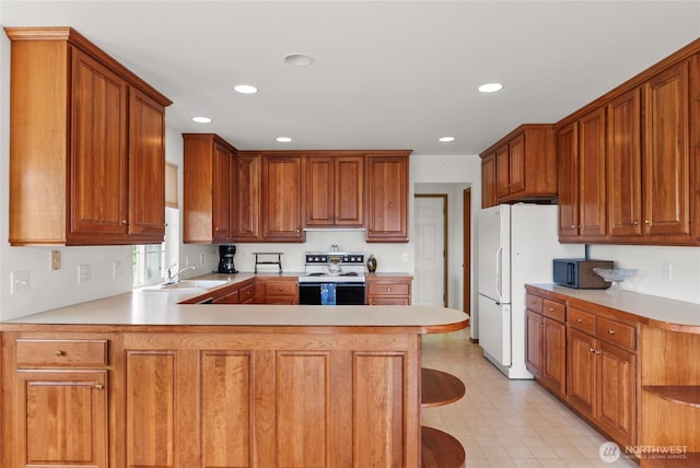 3505 Kimberly Ct, Wenatchee, WA 98801 - kitchen with white appliances, a peninsula, light countertops, recessed lighting, and brown cabinets