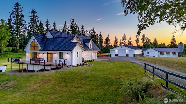 14045 Solberg Rd SE, Yelm, WA 98597 - back of property at dusk featuring a garage, board and batten siding, a yard, a metal roof, and a deck