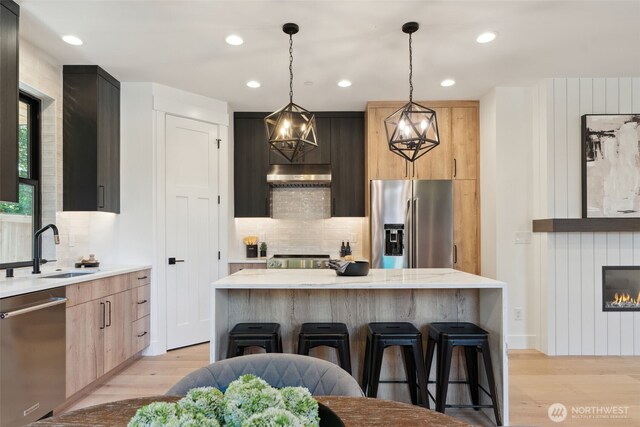 13005 NE 88th St, Kirkland, WA 98033 - kitchen with appliances with stainless steel finishes, under cabinet range hood, light wood-type flooring, a breakfast bar area, and recessed lighting
