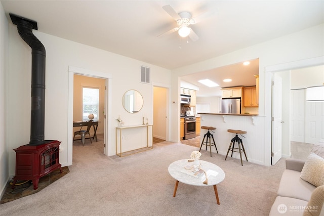2226 King St, Bellingham, WA 98225 - living room with a wood stove, light carpet, and ceiling fan