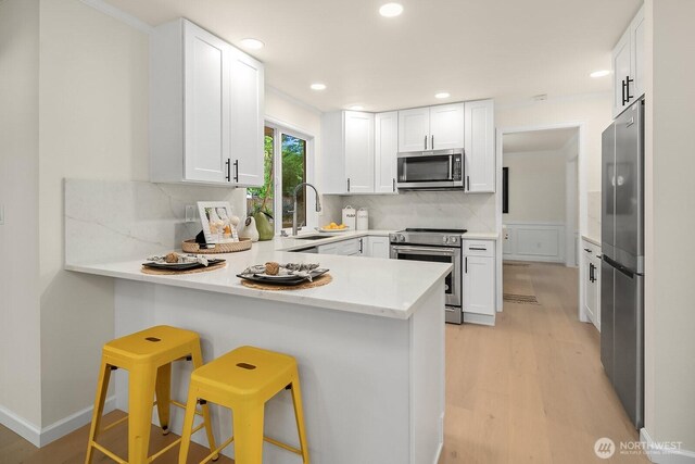 2892 160th Pl NE, Bellevue, WA 98008 - kitchen with appliances with stainless steel finishes, light wood finished floors, a peninsula, backsplash, and recessed lighting