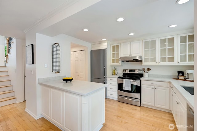 202 W Olympic Pl Unit 201, Seattle, WA 98119 - kitchen featuring appliances with stainless steel finishes, under cabinet range hood, light wood finished floors, white cabinets, and recessed lighting