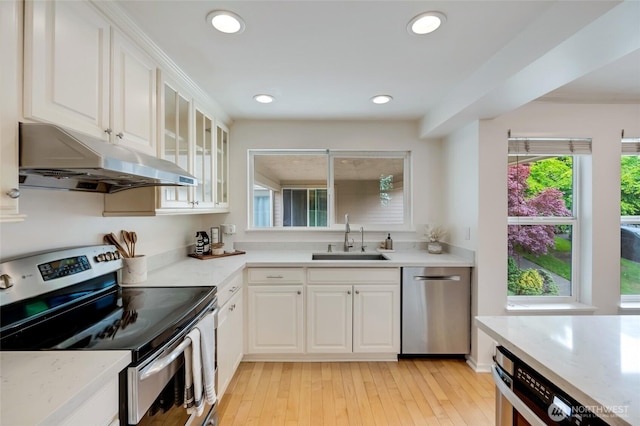 202 W Olympic Pl Unit 201, Seattle, WA 98119 - kitchen featuring appliances with stainless steel finishes, under cabinet range hood, white cabinetry, glass insert cabinets, and recessed lighting