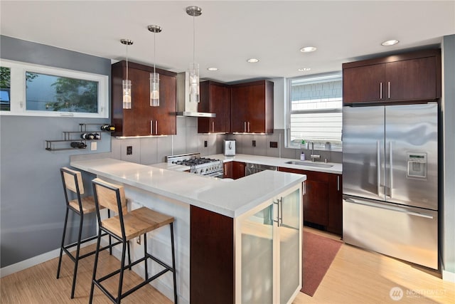1115 24th Ave S, Seattle, WA 98144 - kitchen featuring stainless steel refrigerator with ice dispenser, gas stove, wall chimney range hood, light countertops, and a peninsula