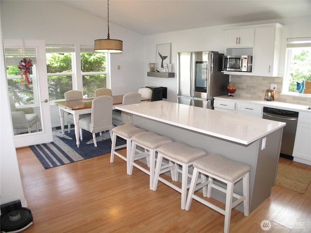32404 G St, Ocean Park, WA 98640 - kitchen featuring appliances with stainless steel finishes, light wood-style floors, a kitchen breakfast bar, vaulted ceiling, and decorative backsplash