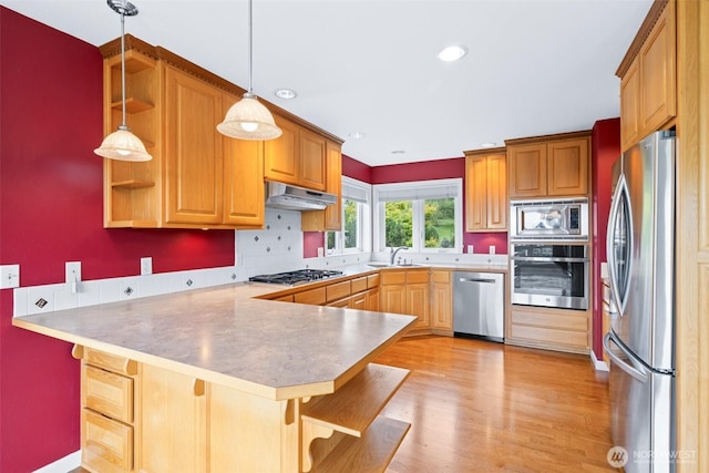93 Old Schoolhouse Rd, Sequim, WA 98382 - kitchen with appliances with stainless steel finishes, a peninsula, under cabinet range hood, tasteful backsplash, and hanging light fixtures
