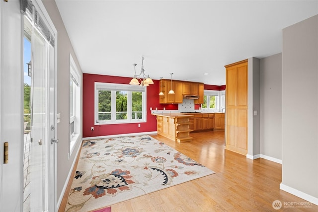 93 Old Schoolhouse Rd, Sequim, WA 98382 - kitchen featuring light wood-style flooring, light countertops, under cabinet range hood, decorative light fixtures, and a chandelier
