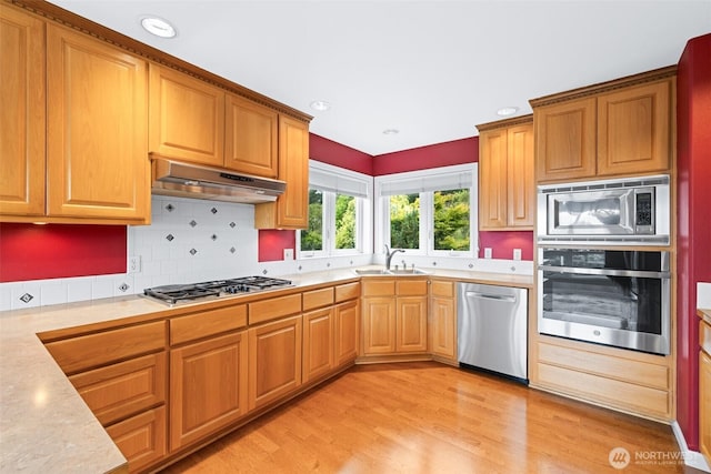 93 Old Schoolhouse Rd, Sequim, WA 98382 - kitchen with stainless steel appliances, under cabinet range hood, light countertops, light wood finished floors, and backsplash