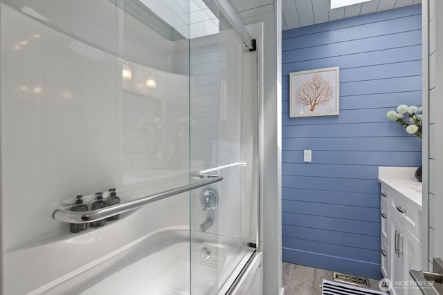 21240 15th Ave S, Des Moines, WA 98198 - full bath with enclosed tub / shower combo, vanity, wood finished floors, and wooden walls