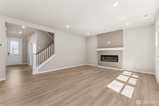 4043 98th Avenue Ct E Unit 24, Edgewood, WA 98371 - unfurnished living room featuring stairs, recessed lighting, light wood-style floors, and a glass covered fireplace