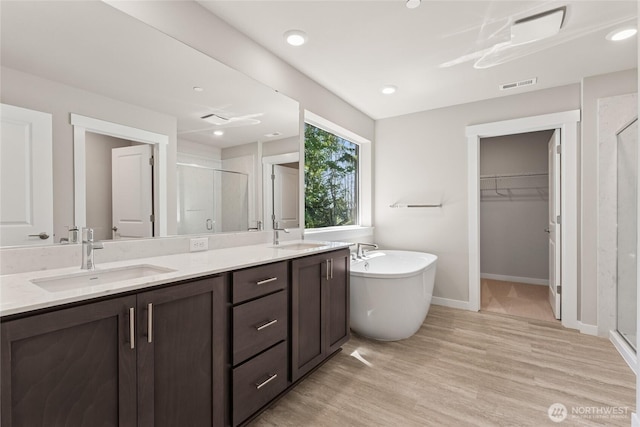 4043 98th Avenue Ct E Unit 24, Edgewood, WA 98371 - bathroom featuring a shower stall, double vanity, a walk in closet, a soaking tub, and wood finished floors