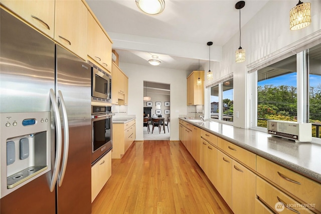 8751 Jones Ave NW, Seattle, WA 98117 - kitchen featuring stainless steel appliances, light brown cabinets, light wood-style floors, hanging light fixtures, and light countertops