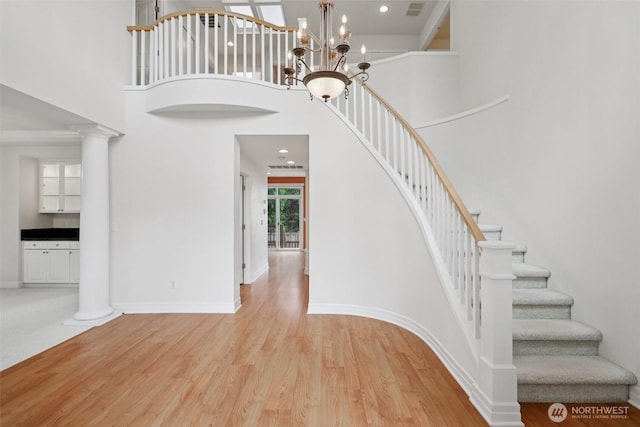 3301 Monterey Ct NE, Renton, WA 98056 - staircase featuring a high ceiling, wood finished floors, a chandelier, and decorative columns