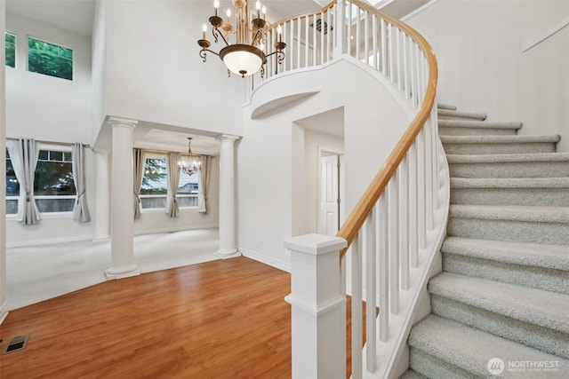 3301 Monterey Ct NE, Renton, WA 98056 - stairs featuring a chandelier, decorative columns, wood finished floors, and a high ceiling