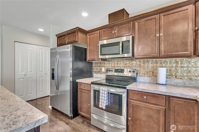 19802 69th Avenue Ct E, Spanaway, WA 98387 - kitchen with appliances with stainless steel finishes, light countertops, tasteful backsplash, light wood-type flooring, and recessed lighting