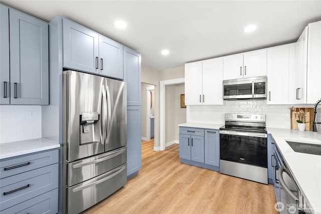 5116 N 40th St, Tacoma, WA 98407 - kitchen with appliances with stainless steel finishes, backsplash, light wood-style floors, recessed lighting, and white cabinetry