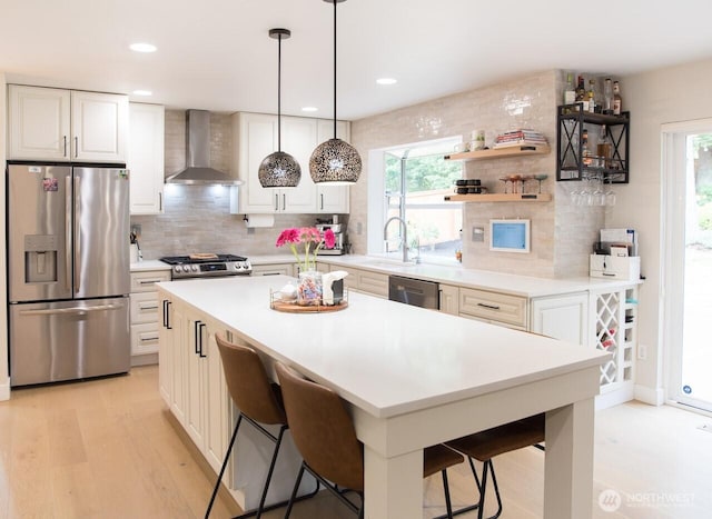 903 198th Ave E, Lake Tapps, WA 98391 - kitchen with appliances with stainless steel finishes, wall chimney exhaust hood, a breakfast bar area, backsplash, and recessed lighting